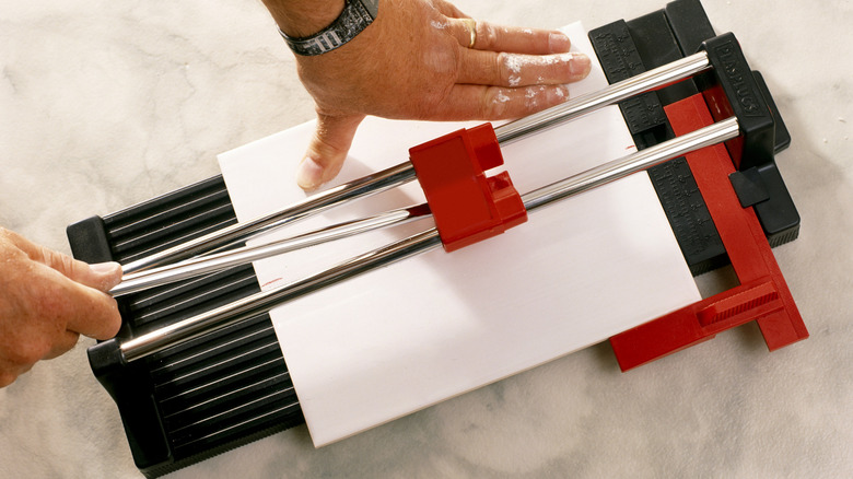 Person cutting a white tile