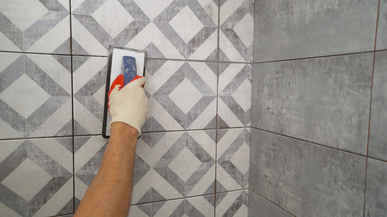 Person grouting tile on a wall