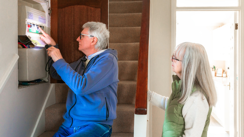 An older couple taking a look at their circuit breaker box