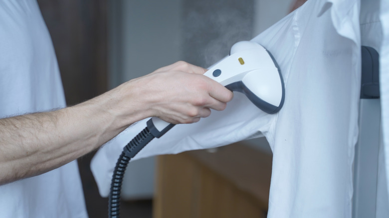 Man using a steam cleaner on shirt