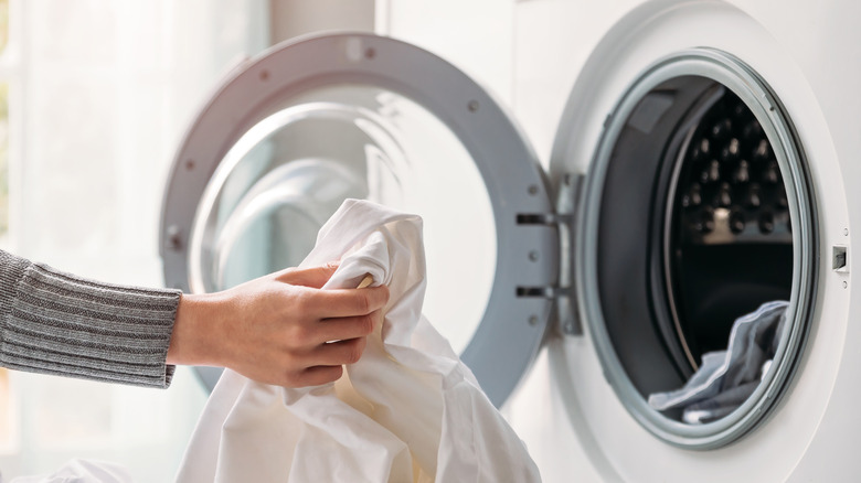 A woman loading a washing machine with laundry