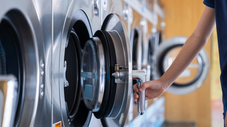 A person opening one of a line of laundry machines