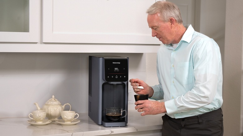 Man getting hot water for his coffee with Waterdrop Filter A1 Dispenser