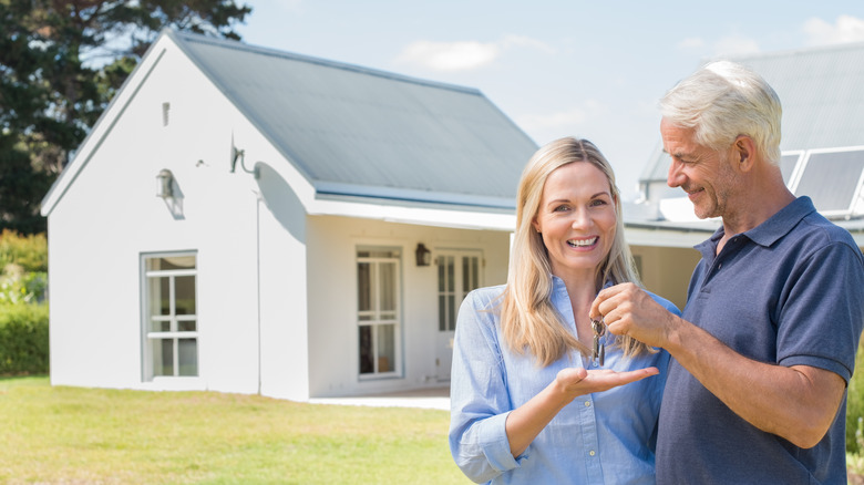 Older man giving a woman keys to a house