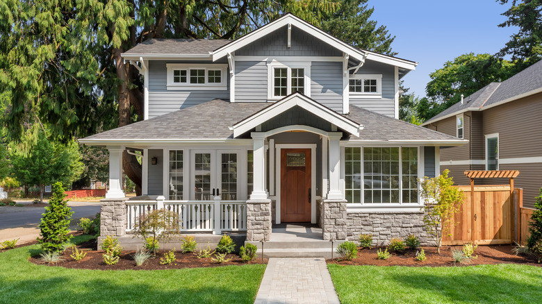 Large newly built grey home with stone bottom and white trim