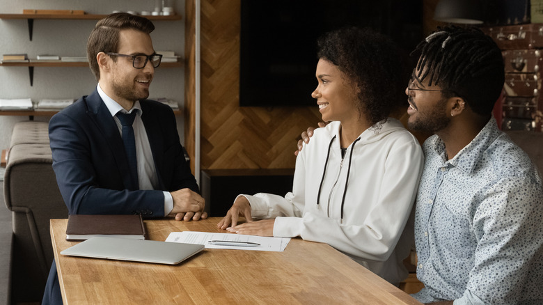 Black home buyers and white agent at table