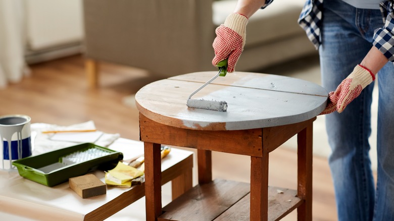 man painting an end table