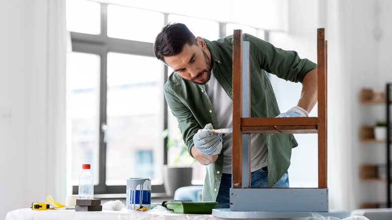 man painting a chair