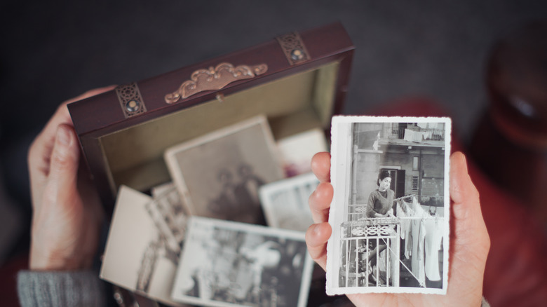 hands holding old photos from a box.