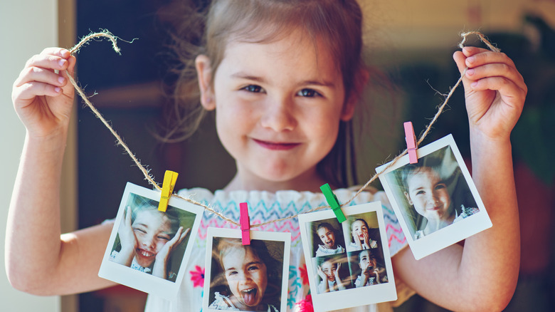 girl holding photos on string