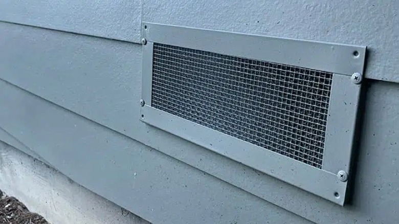 Fire-resistant foundation vent against gray house siding