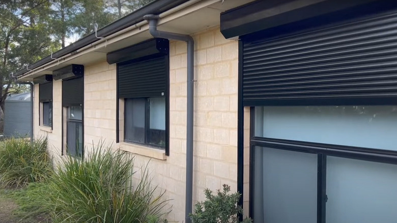 single story house with roller shutters over glass windows