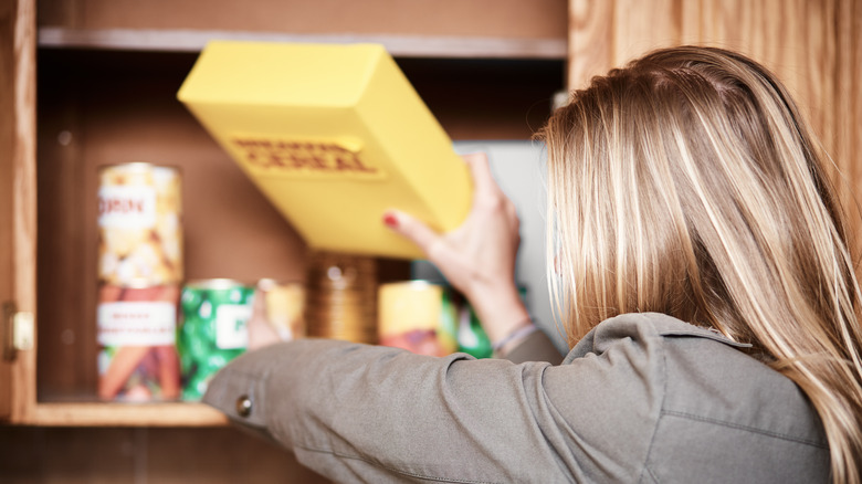 Person putting cereal on shelf