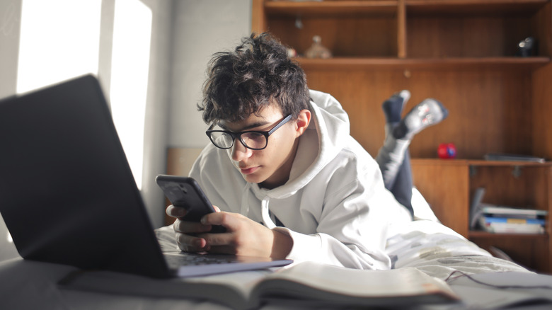 Teen boy on phone and laptop 