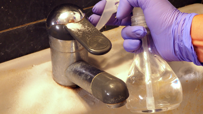 A person uses cleaning spray on a bathroom sink