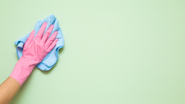 Gloved hand cleaning a wall