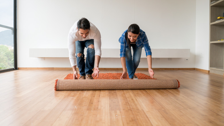 couple unrolling rug wood floor