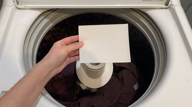 Hand placing detergent sheet in washer