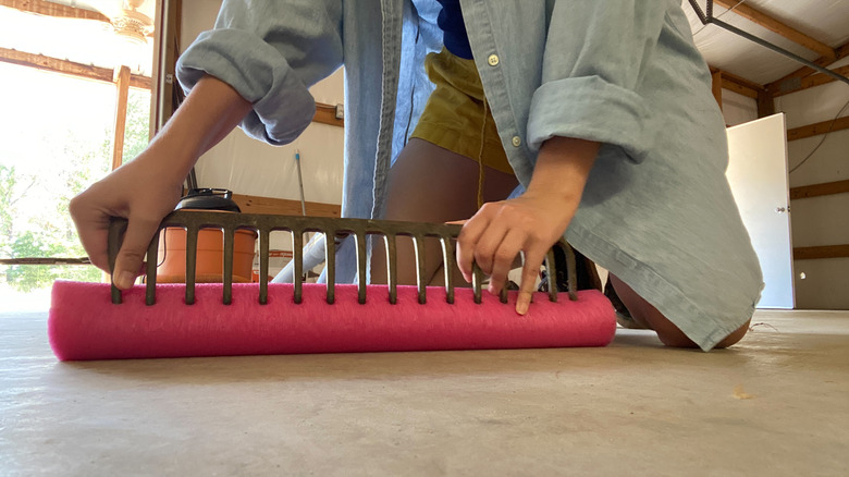 Person kneeling with hands on rake