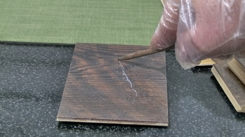 Damaging flooring with scratch awl