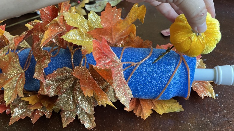 Hand inserting fall decor into foam