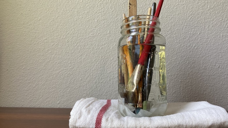 Paintbrushes soaking in glass jar