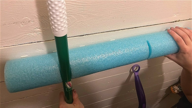 Hanging broom on pool noodle 