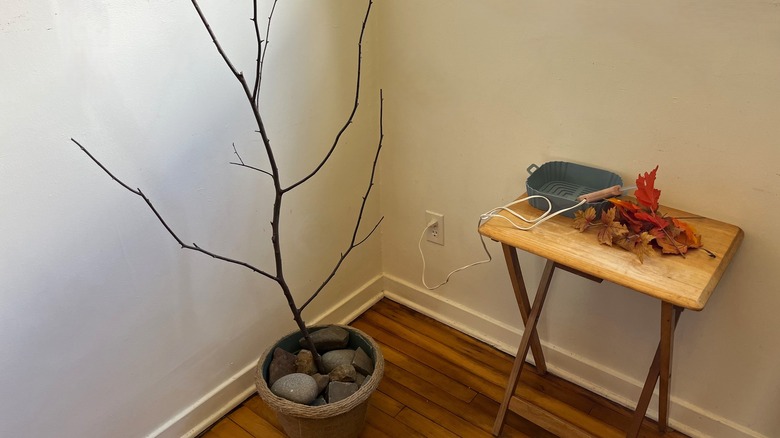 Bare branch in planter and table with leaves