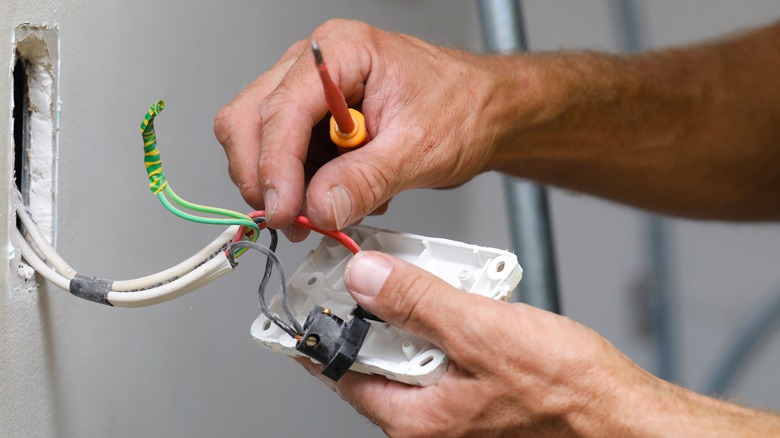 Hands fixing home electrical wiring