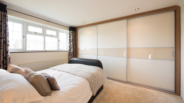 A neutral bedroom with bypass doors on the wall-to-wall closet