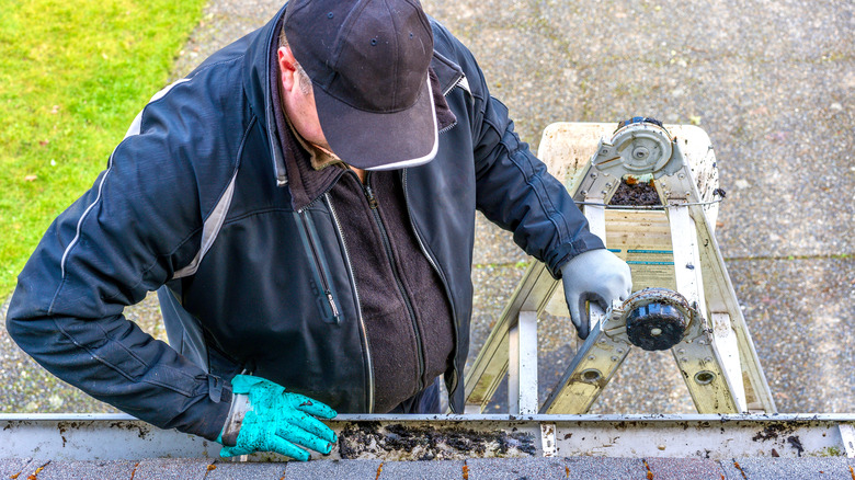 man cleaning gutters and checking eaves