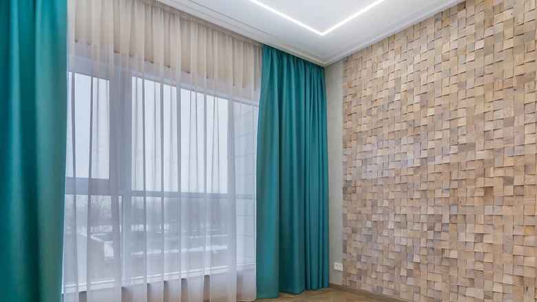 Turquoise side panels hung over translucent white curtains