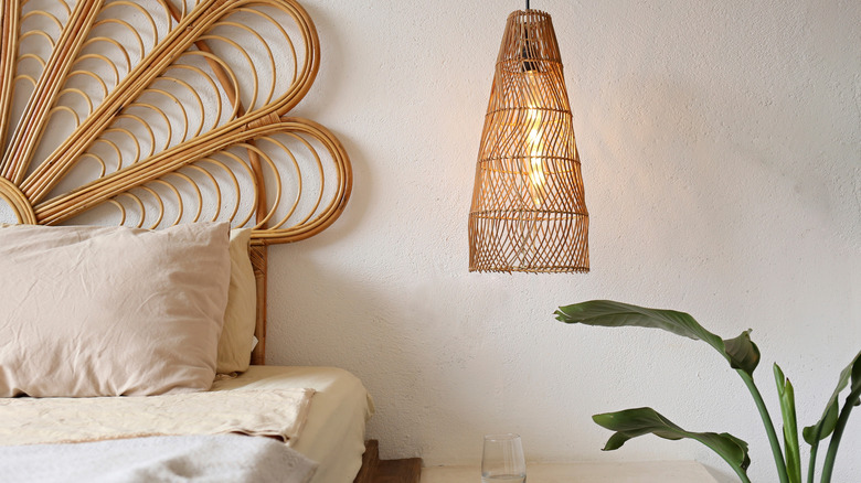 A low-hanging rattan bedside table lamp next to bed.