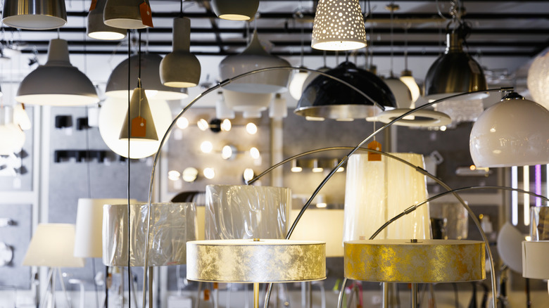 A woman screwing a light bulb into a hanging lamp.