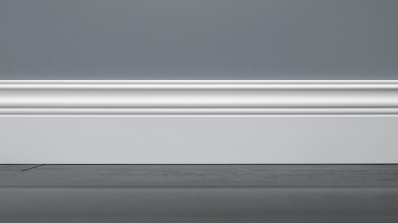 White sculpted baseboard along a gray wall