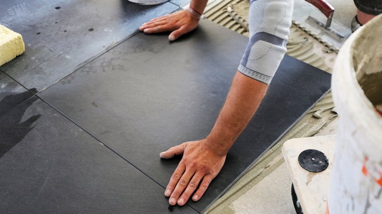 contractor laying large floor tiles