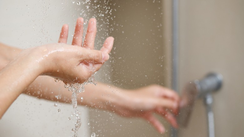 Hand feels water from shower