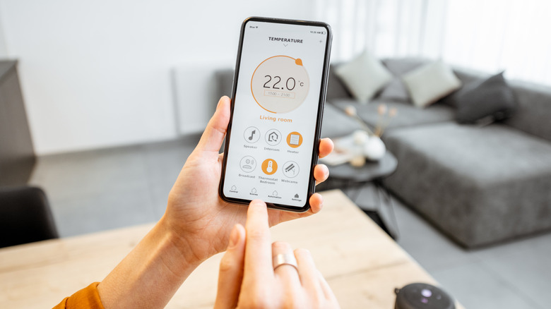 person controlling thermostat from phone