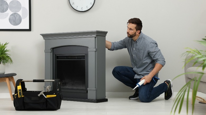 Man installing gray electric fireplace 
