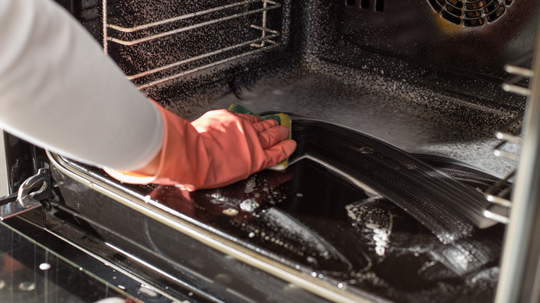 Person wiping cleaner in oven