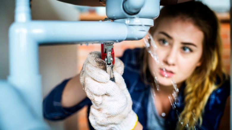 woman fixing a burst pipe