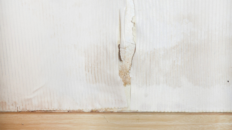 White wallpaper with brown discoloration and cracks