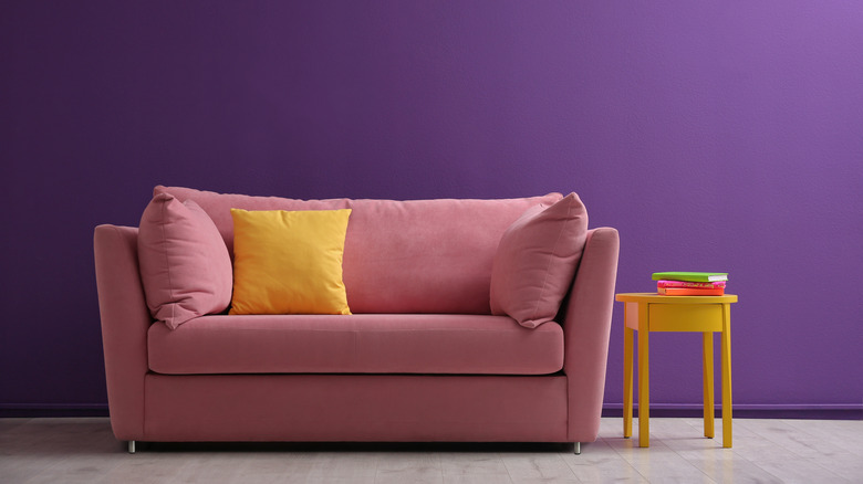 pink couch against purple wall 