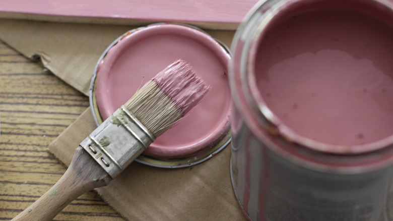 A can of pink paint with a paint brush