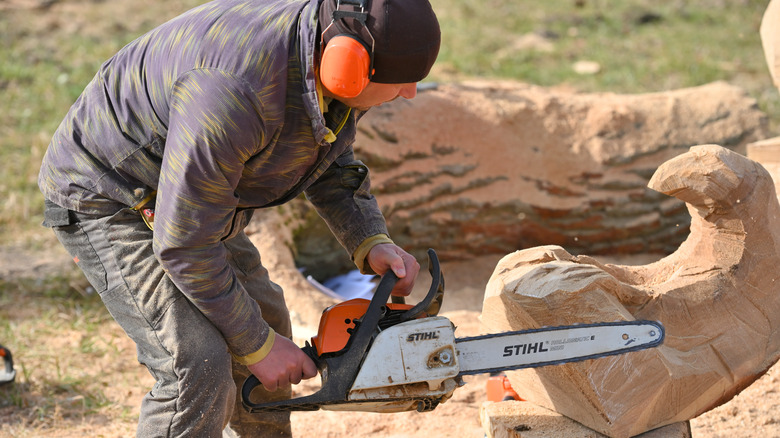 Man using Stihl chainsaw to cut wood