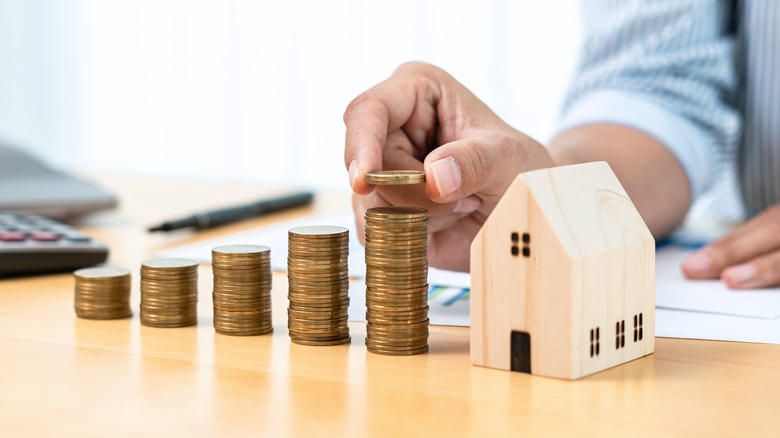 hand stacking coins and house