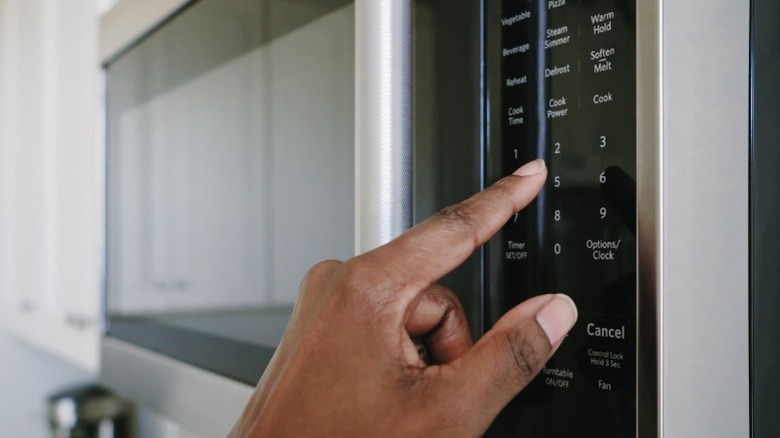 Hand pressing buttons on OTR microwave