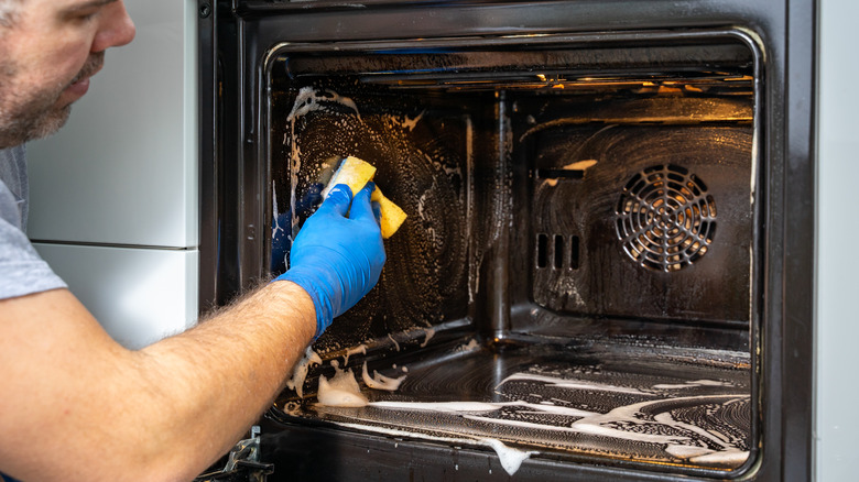 man cleaning oven with sponge