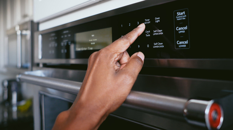 person pressing settings on oven 