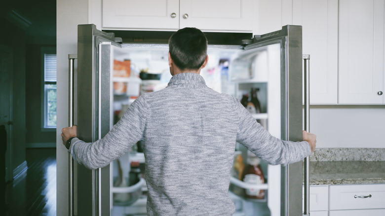 man opening both doors of refrigerator